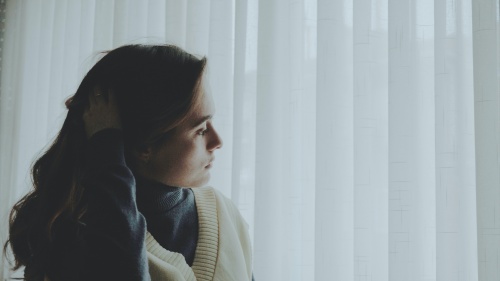 A woman looking curtains outside.