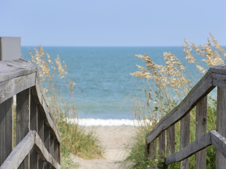 a wooden walkway leading towards the sand and ocean