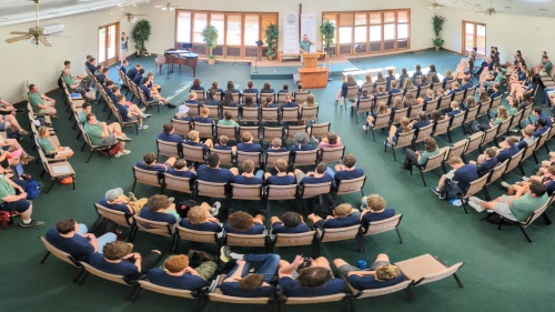 a large group of people seated in a semicircle indoors