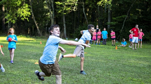 a group of children running and playing a game in a field