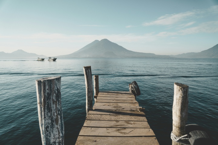 a dock leading out to a body of water with a mountain on the horizon