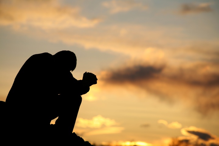 A person bent over praying.