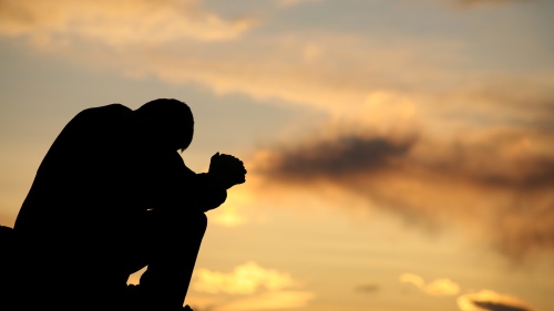 A person bent over praying.