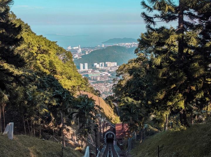 Green mountains on mountain during daytime with a tunnel and a railroad running down the center