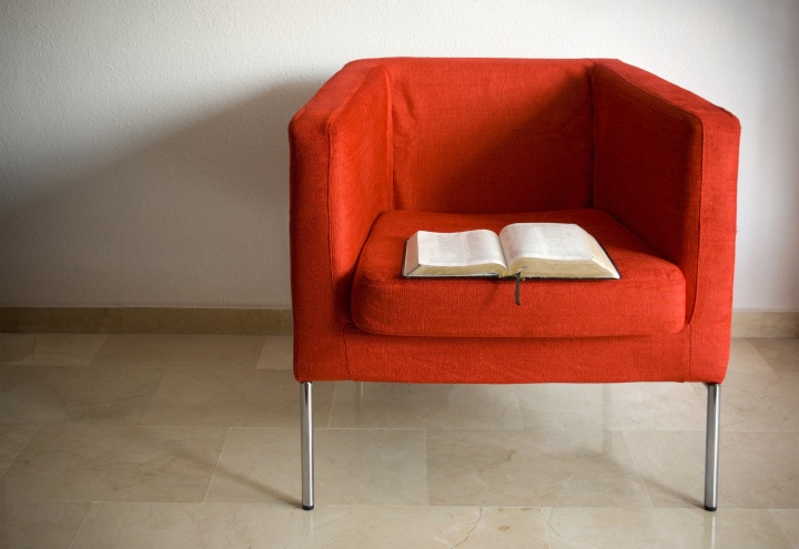 Bible laying in an empty red chair.