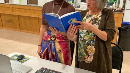 two women singing hymns while standing at the sound table