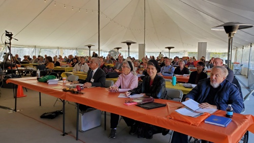 people sitting at services under a big tent