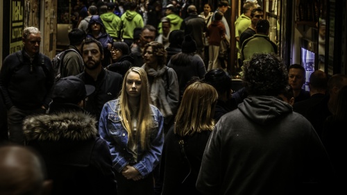 A woman walking in a crowded alley with numerous people.