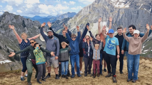 a group of hikers standing on mountainous terrain with mountains in the background